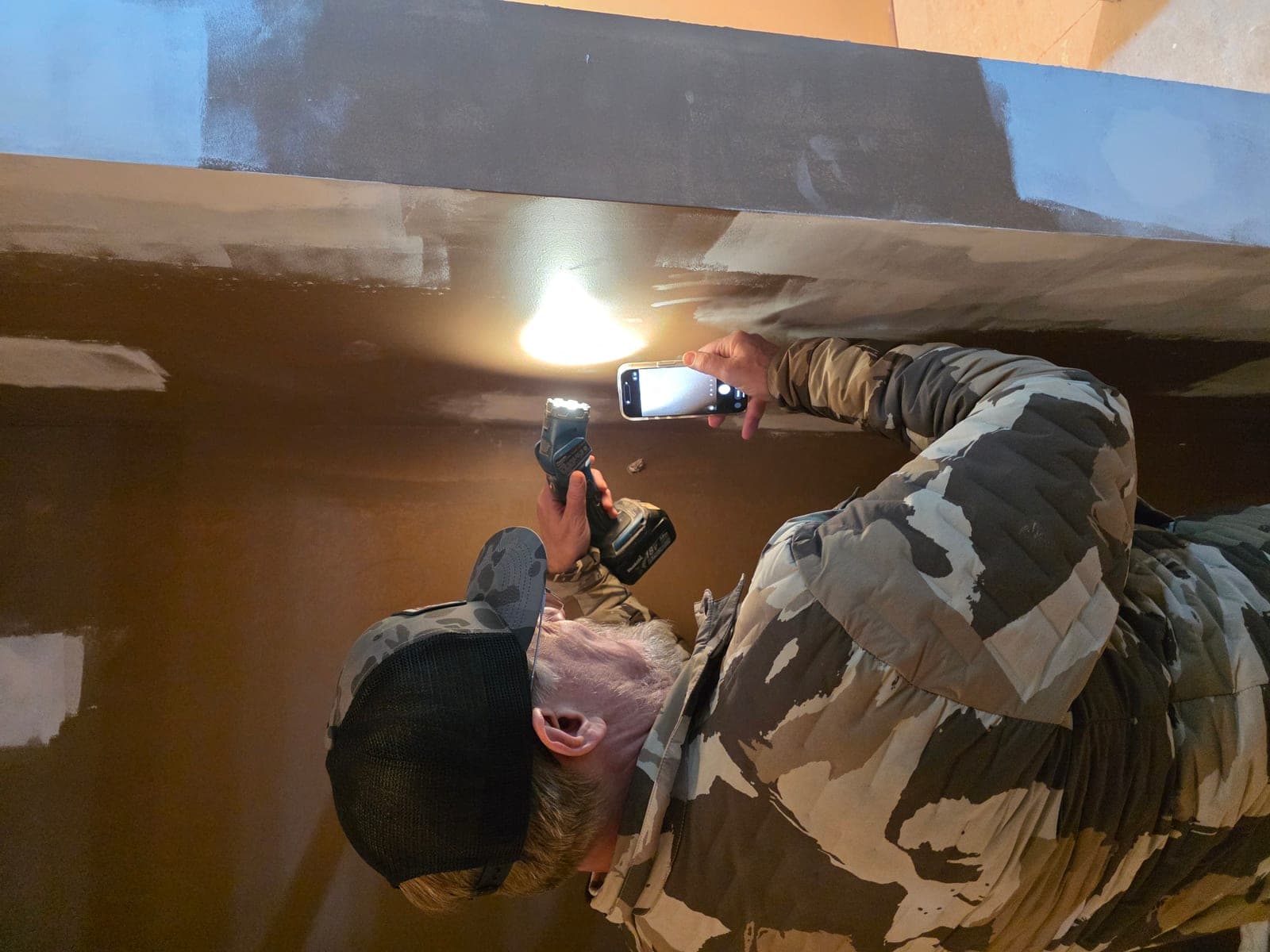 Mission Painting crew member using a high-intensity pan light to inspect painted surfaces for imperfections
